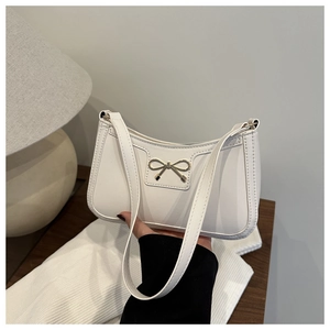 Dettaglio della borsa a mezzaluna in PU bianco con fiocco dorato e sottile tracolla