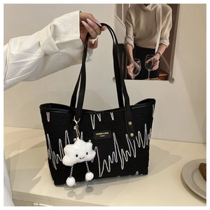 Close-up of black quilted tote bag with colorful wave stitching and cloud charm