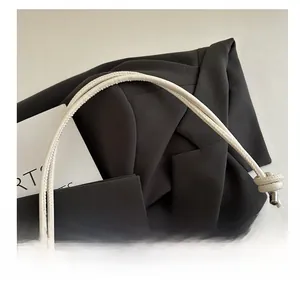 Detail showing white bucket bag with wave texture and black bow accents and knotted handle