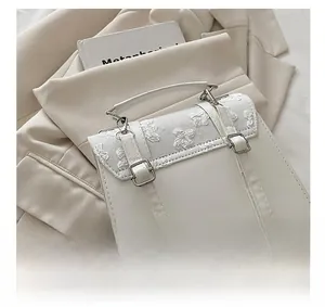 Detail showing the adjustable shoulder strap and white butterfly lace embroidery on the bag