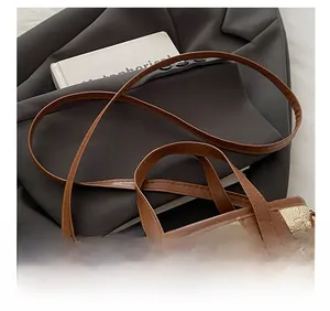 Details der beigen Leder-Beuteltasche mit Bienenrelief und verstellbarem Gurt