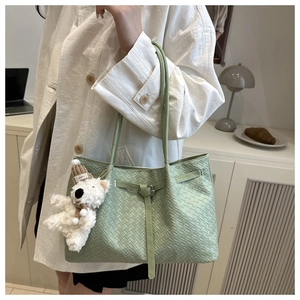 Détail d'un sac cabas tissé vert clair avec un charmant ours en peluche en mode de vie
