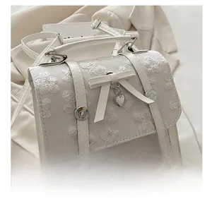 Close-up of white floral textured fabric bag with bow detail and silver heart pendant
