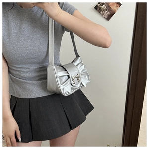 Detail of metallic silver underarm bag featuring a 3D bow and chrome buckle