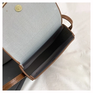 Detail view of brown saddle bag showing interior fabric lining and gold magnetic closure