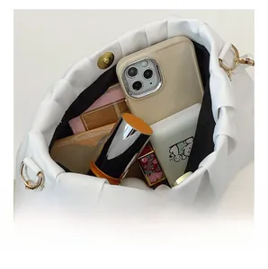 Macro view of white pleated cloud bag interior showing pearl strap and daily essentials