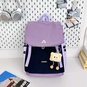 Outdoor color-block backpack in purple and navy blue with a plush monster keychain