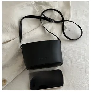 Detail of black leather bucket bag with debossed logo next to a phone for size reference