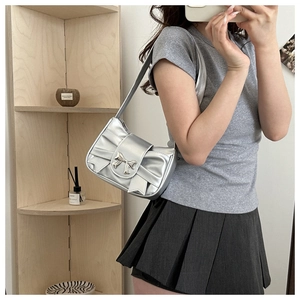 Close-up of metallic silver bow shoulder bag with mirror faux leather and bow buckle