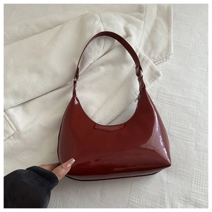 Detailed close-up of dark red patent leather hobo bag with glossy finish and silver buckle
