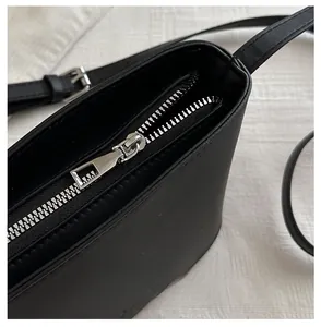 Detail of a smooth silver zipper closure on a black leather shoulder bucket bag