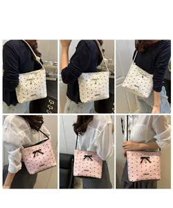 Detail of quilted tote bag with bow pendant and metal heart charm in white and pink