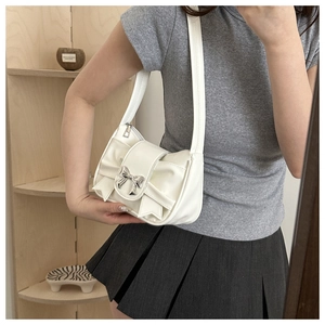 Detail showing white shoulder bag with bow-shaped flap and silver metal bow buckle