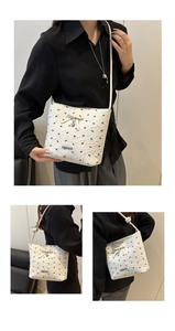 Detail of white bucket bag featuring floral jacquard texture and bow heart pendant