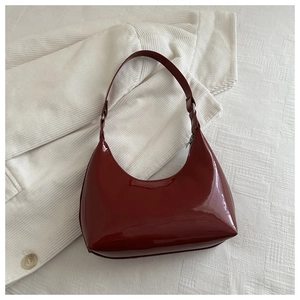 Top view of deep red patent leather handbag showing sleek texture and silver zipper