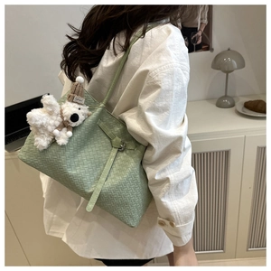 Detail of sage green woven tote bag with adjustable strap and cute plush bear charm