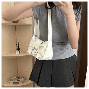 Detail of white pleated shoulder bag featuring a large bow and silver buckle detail