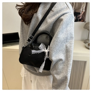 Dettaglio della mini borsa Boston nera con fiocco in pizzo bianco e tracolla regolabile
