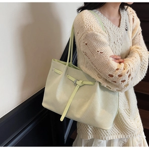 Gros plan du sac cabas vert menthe en cuir tressé sur l'épaule du mannequin