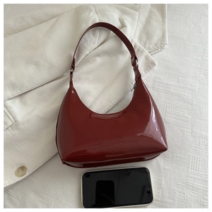 Close-up of deep burgundy patent leather crescent bag with glossy mirror finish