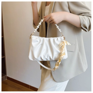 Detail of white pleated cloud bag with pearl handle and beige satin ribbon accent