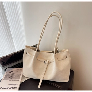 Détail d'un sac seau tressé crème avec boucle en cuir et longues bretelles d'épaule