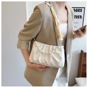 Detail of white pleated cloud bag with elegant pearl strap and woven shoulder strap