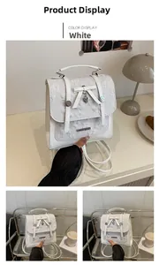 Detail of white backpack with 3D butterfly embroidery and heart-shaped metal pendant