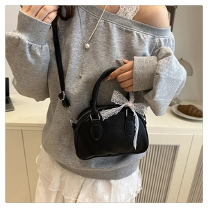 Dettaglio mini borsa a bauletto nera con fiocco in pizzo e motivi a cuore in pelle PU