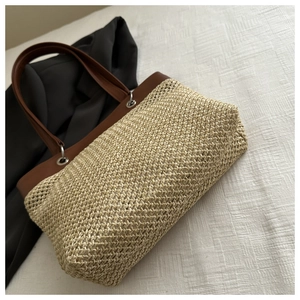 Close-up of handmade straw tote with leather handles and silver ring fasteners