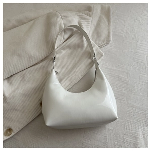 Close-up of a white patent leather hobo bag with adjustable strap and silver hardware