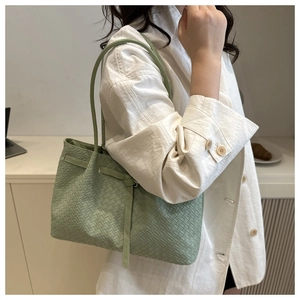 Detail view of woven leather texture on mint green tote bag styled with white blazer