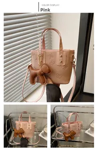 Detalle de bolso cubo rosa con relieve de mariposas y un colgante de perrito
