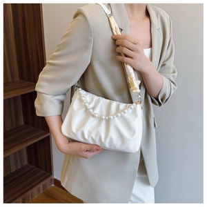 Detail of white pleated cloud bag with pearl chain and silk scarf wrapped handle