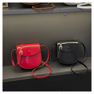 Detail showing two glossy saddle bags in red and black with adjustable golden buckles
