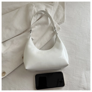 Macro shot of white patent leather hobo bag with smartphone for size comparison