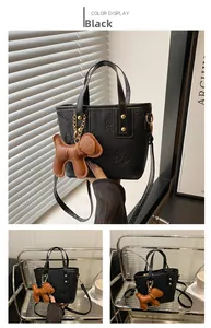 Detalle de bolso cubo negro con lazo, colgante de perro y herrajes dorados elegantes