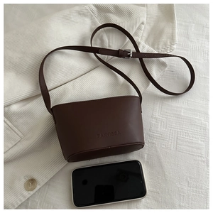 Macro detail of dark brown bucket bag with embossed logo and adjustable silver buckle