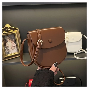 Detailed view of dark brown saddle bag with polished finish and decorative buckle