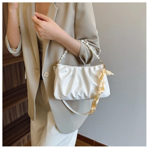 Detail of white pleated cloud bag featuring premium pearl handle and yellow silk scarf