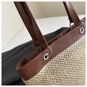 Detail of raffia woven texture and brown leather strap with silver metal grommets