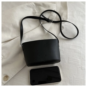 Detailed view of black leather bucket bag with logo and phone for size reference