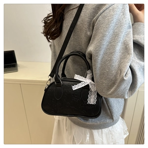 Dettaglio mini borsa bowling nera in PU goffrato con fiocco di pizzo e tracolla