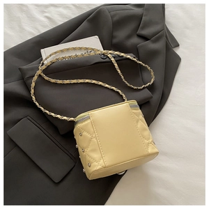 Close-up of beige quilted box bag with silver rivets and metal chain on a grey blazer