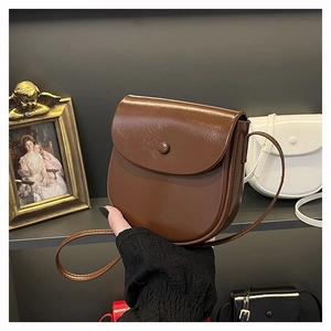 Close-up of a matte leather saddle bag featuring fine stitching and a classic flap design