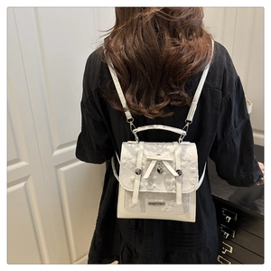 Detail of white lace mini backpack with bow decoration and heart metal pendant