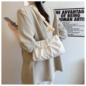 Detail of white ruched cloud bag with pearl chain and silk scarf handle on model