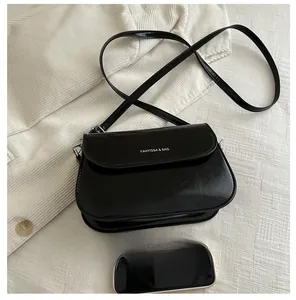 Top view of black patent leather crossbody bag with smartphone for size comparison