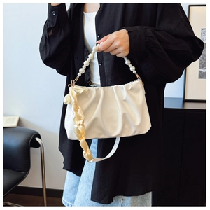 Close-up of white ruched bag with large pearl handle and yellow silk ribbon detail