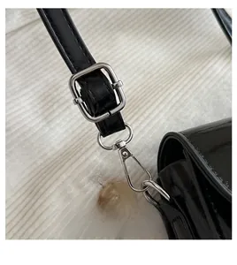 Detail of adjustable glossy leather shoulder strap with silver buckle and metal hook